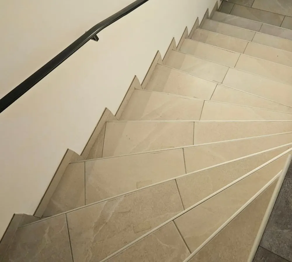 Treppenhaus mit hellen Fliesenstufen vor der Reinigung